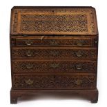 A GEORGIAN OAK BUREAU having extensive carved geometric decoration, fall front opening to reveal