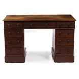 AN EDWARDIAN MAHOGANY PEDESTAL DESK with nine drawers, having turned handles and raised on plinth