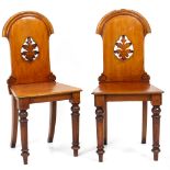 A PAIR OF VICTORIAN MAHOGANY HALL CHAIRS the backs pierced with leaf designs and raised on turned