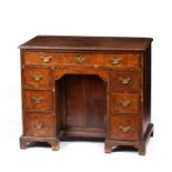 A QUEEN ANNE STYLE FIGURED WALNUT AND MAHOGANY VENEERED KNEEHOLE DESK with an arrangement of seven