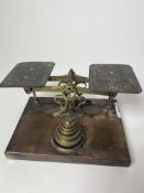 A SET OF BRASS POSTAL SCALES with graduated weights, on a rectangular plinth base, 17.5cm wide At