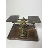 A SET OF BRASS POSTAL SCALES with graduated weights, on a rectangular plinth base, 17.5cm wide At