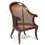 A REGENCY MAHOGANY BERGERE LIBRARY ARMCHAIR with caned back and seat and sabre supports