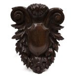 A CARVED HARDWOOD WALL BRACKET with central shield and scrolling surround, 33cm wide x 42cm high