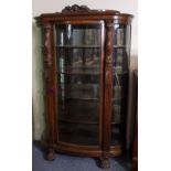 AN EARLY 20TH CENTURY CARVED OAK GLAZED BOW FRONTED CABINET with carved classical dolphin, fluted