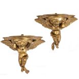 A PAIR OF 19TH CENTURY GILDED WALL BRACKETS in the form of winged putti, each 30cm wide x 17cm