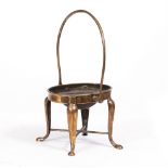 AN ANTIQUE BELL METAL STAND with a large looping handle, four legs united by an X stretcher, 22cm