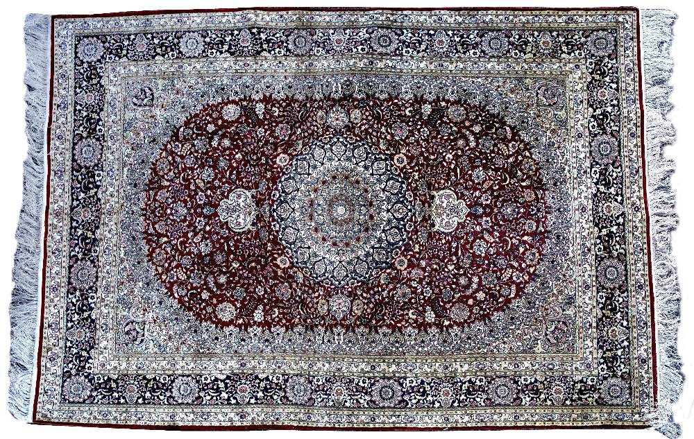 AN ORIENTAL SILK RED GROUND RUG with circular decoration to the floral field within a multiple