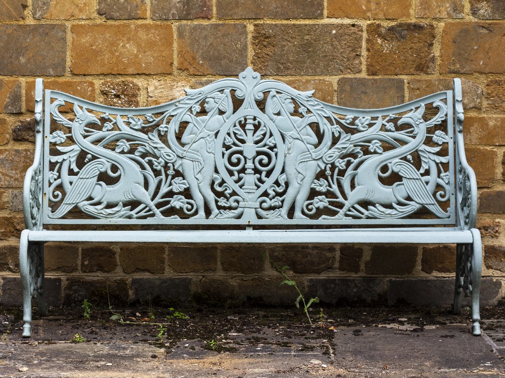 A VICTORIAN GREEN PAINTED CAST IRON GARDEN SEAT the pierced back decorated with men armed with