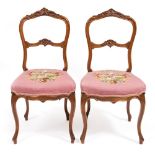 A PAIR OF 18TH CENTURY STYLE FRENCH WALNUT SIDE CHAIRS with carved backs, needlework upholstered