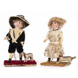 A PAIR OF VICTORIAN DOLLS a boy and a girl, each dressed in period costume and mounted on a