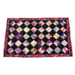 A RECTANGULAR PATCHWORK BEDCOVER OR HANGING with geometric diamond shaped motifs within a rose