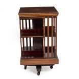 AN EDWARDIAN MAHOGANY ROTATING BOOKCASE with decorative floral inlay to the top, cast iron