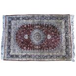 AN ORIENTAL SILK RED GROUND RUG with circular decoration to the floral field within a multiple