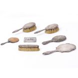 THREE SILVER BACKED DRESSING BRUSHES, a silver backed mirror, a white metal cigarette case and