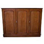 A VICTORIAN MAHOGANY TRIPLE WARDROBE with three panelled doors opening to reveal linen slides, a