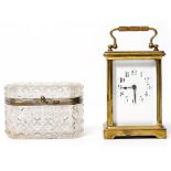 A SMALL CARRIAGE TIMEPIECE with arabic numerals, 14.5cm high with handle up together with a glass