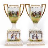 TWO CONTINENTAL PORCELAIN VASES decorated with courtly figures picnicking, mounted on a plinth