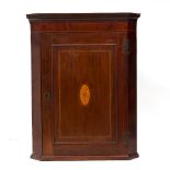 A 19TH CENTURY MAHOGANY HANGING CORNER CUPBOARD with decorative inlaid paterae to the door, 77cm