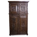 A 20TH CENTURY 17TH CENTURY STYLE CARVED OAK CUPBOARD with panel doors opening to reveal linen
