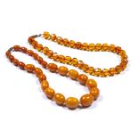 Two amber bead necklaces Chinese the first of butterscotch colour comprising single strand of