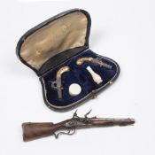 Cased pair of miniature apprentice percussion cap pistols with engraved yellow metal handles and