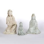 Three dehua figures of Guanyin Chinese, 19th Century two modelled holding a scroll to one hand, with