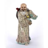 Porcelain model of Lohan Chinese dressed in flowing robes with one hand holding a shoe, with his hat