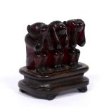 Amber carving of three monkeys Chinese, circa 1900 on a hardwood stand, 6.5cm across, 7.5cm high