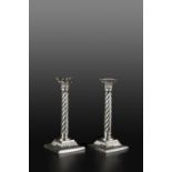 A PAIR OF VICTORIAN SILVER CANDLESTICKS, with spirally fluted columns and corinthian capitals, on