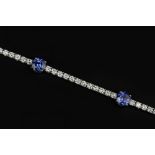 A TANZANITE AND DIAMOND LINE BRACELET, designed as a line of uniform round brilliant-cut diamonds in