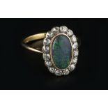 AN OPAL AND DIAMOND CLUSTER RING, the oval cabochon black opal in millegrain collet setting,