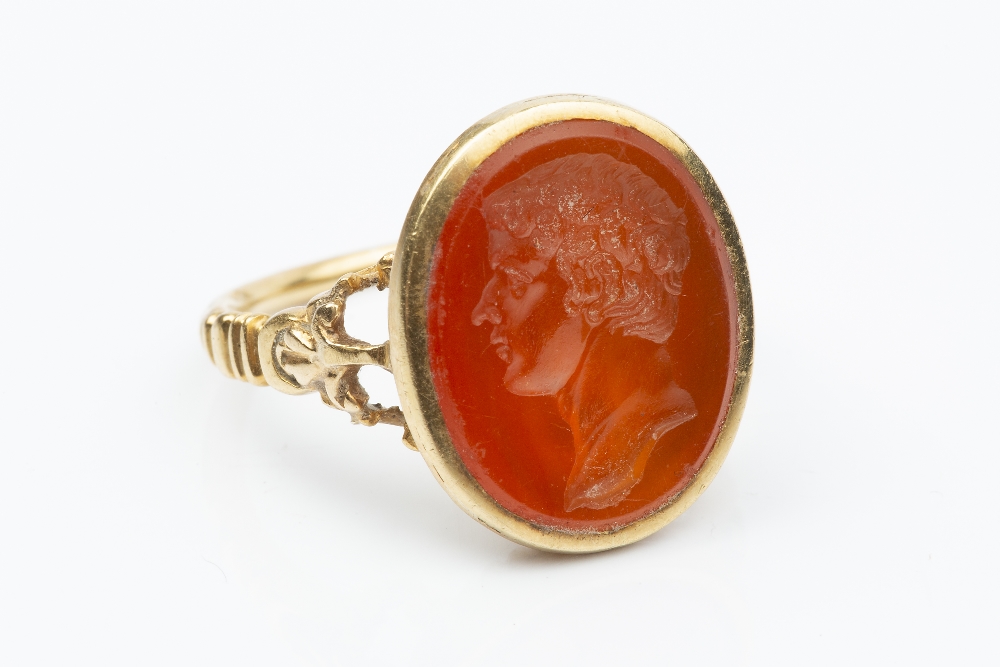 A 19TH CENTURY HARDSTONE INTAGLIO RING, the oval cornelian panel incised with a classical male