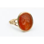 A 19TH CENTURY HARDSTONE INTAGLIO RING, the oval cornelian panel incised with a classical male