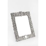 A LATE VICTORIAN SILVER RECTANGULAR EASEL MIRROR, pierce decorated and embossed with masks, putti,