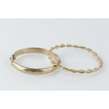 TWO 9CT GOLD BANGLES, the first of continuous twist design, by Unoaerre, the second of hinged oval