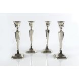 A SET OF FOUR SILVER CANDLESTICKS, with knopped and tapered stems, on chamfered, weighted square