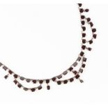 A GARNET RIVIÈRE AND SWAG NECKLACE, designed as a line of graduated cushion-shaped mixed-cut garnets