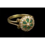 AN EMERALD AND DIAMOND PANEL RING, the circular panel with a cluster of pear-shaped emeralds and