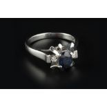 A SAPPHIRE AND DIAMOND DRESS RING, the oval mixed-cut sapphire in abstract claw setting, between two