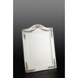 AN EDWARDIAN SILVER EASEL DRESSING TABLE MIRROR, with arched top, applied with ribbon tied