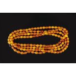 AN AMBER BEAD NECKLACE, comprising a single strand of uniform amber beads, measuring approximately