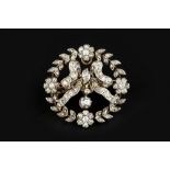 A DIAMOND BROOCH/PENDANT, designed as a wreath of flowerheads and foliage enclosing a ribbon bow,