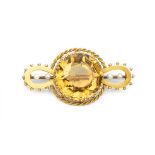 A LATE VICTORIAN CITRINE AND PEARL BROOCH, the shaped openwork panel centred with a circular mixed-