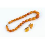 AN AMBER BEAD NECKLACE, comprising a single strand of amber beads, graduating from approximately