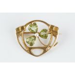 A PERIDOT AND HALF PEARL PANEL BROOCH, the openwork panel centred with a three-leaf clover of
