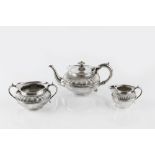 AN EDWARDIAN SILVER THREE PIECE BACHELOR'S TEA SERVICE, of compressed, half-lobed design, the teapot