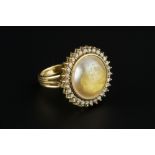 A DIAMOND SET CLUSTER RING, centred with a simulated pearl, bordered by claw set round brilliant-cut