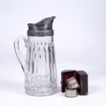A GLASS AND SILVER PLATE MOUNTED CORDIAL JUG with embossed scroll collar and side handle, 29cm