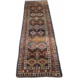 AN OLD KURDISH HALL RUG decorated with a central pattern of polychrome hooked medallions within a